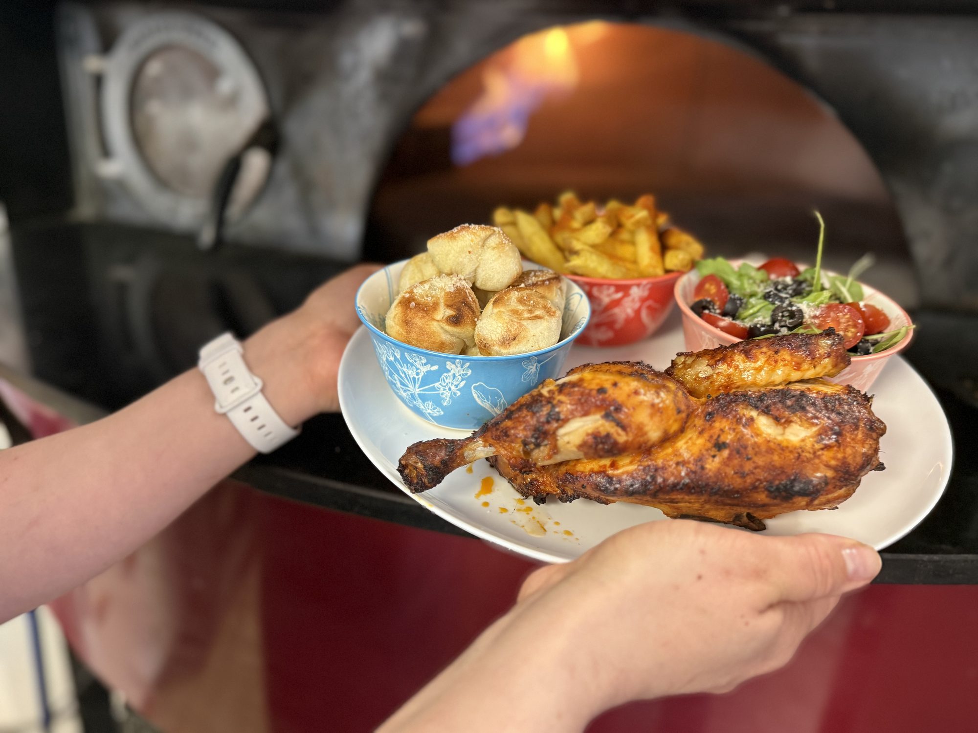 Plate of bowls — salad, fries and dough balls — by the oven