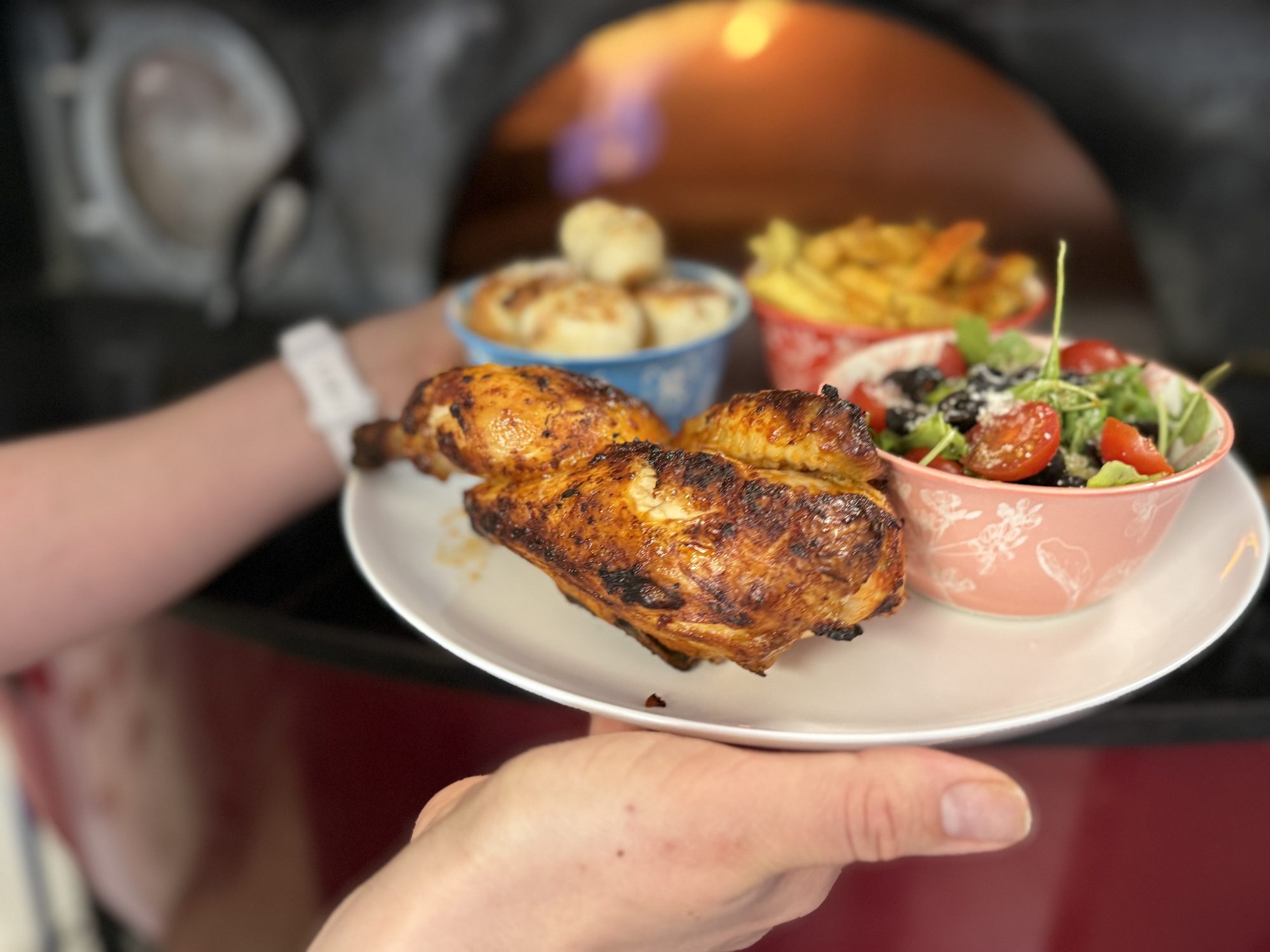 Wood-fired half chicken with sides held by the oven